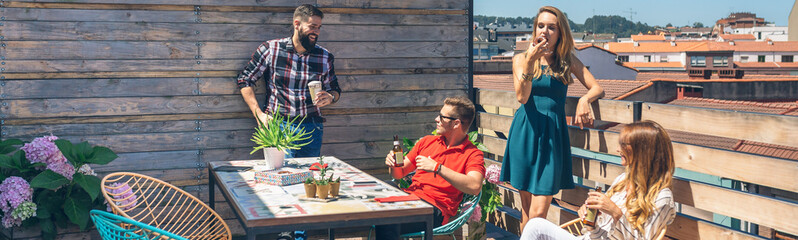 Group of friends talking and drinking at a party on a terrace