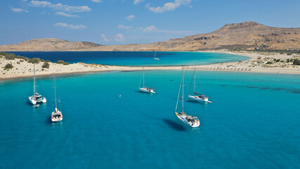 Aerial drone photo of paradise turquoise sandy beach and bay of Simos in island of Elafonisos visited by yachts and sail boats, South Peloponnese, Lakonia, Greece