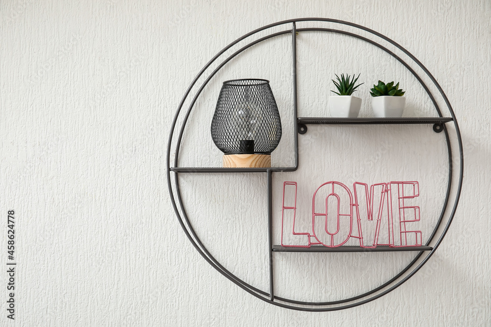 Stylish shelf with lamp and decor hanging on light wall