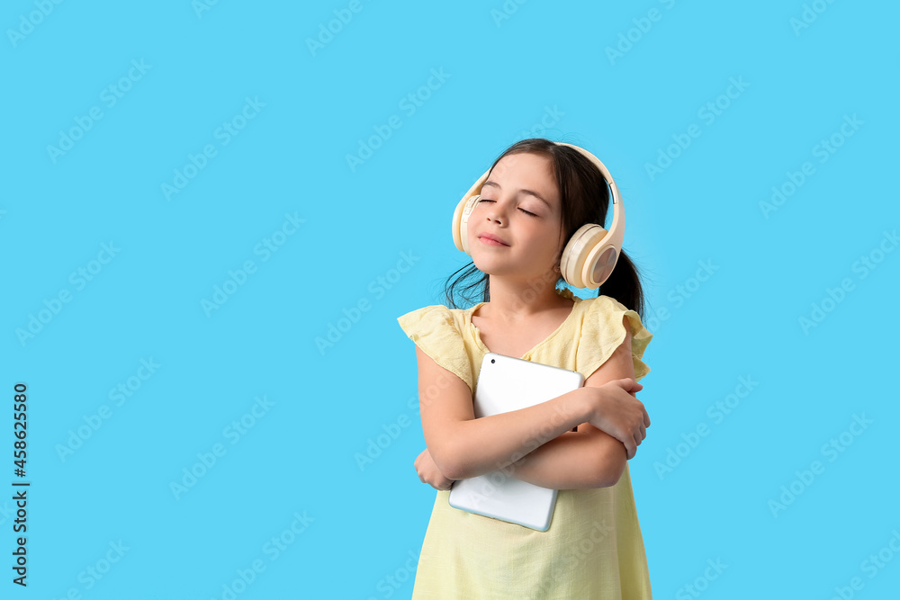 Little girl with tablet computer and headphones on color background