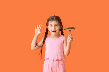 Emotional little girl with tasty sausage on red background