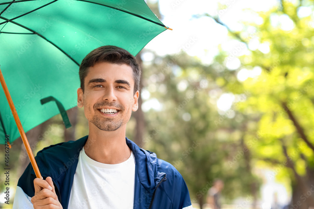 Handsome young man with umbrella in park