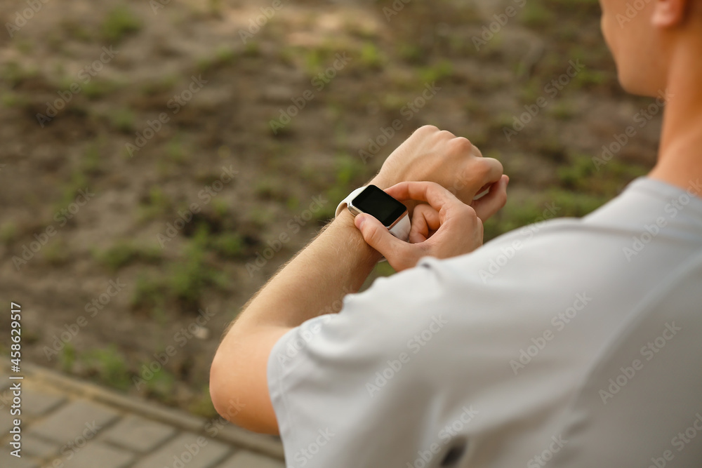 Sporty male runner checking pulse outdoors