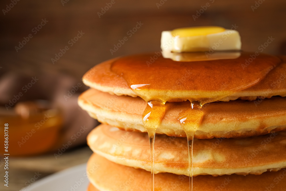 Tasty pancakes with honey and butter on table, closeup