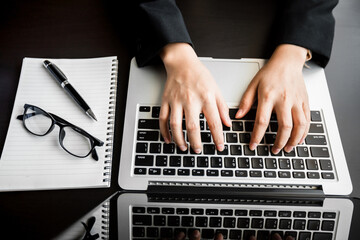 Canvas Print - close up of businesswomen working online on laptop computer with a notebook, typing text send e-mail or chatting, lifestyle freelancer, create content media, telework, telecommuting, work from home.