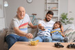 © Pixel-Shot - Man, his little son and father watching TV at home
