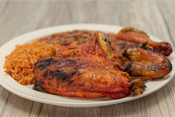 Half a chicken roasted to perfection on a plate with Mexican rice and beans for a hearty meal