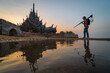 Professional photographer with camera and tripod at summer, sanctuary of truth on the seashore in pattaya, thailand.