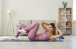 © Studio Romantic - Young athletic woman doing cross training crunches to activate muscle and abs training. Woman in stylish pink sportswear trains at home in room on floor on sports mat. Concept of health and body care.