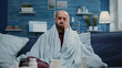 © DC Studio - Close up of ill man with headache rubbing temples while looking at camera. Portrait of sick adult with coronavirus symptoms and migraine while feeling cold with blanket. Person with flu