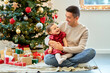 © Syda Productions - winter holidays and family concept - happy middle-aged father and baby daughter with gifts and christmas tree at home