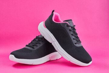 Female sneakers for run on pink background. Fashion black running shoe, sneaker or trainer. Women's fitness, sport, training concept.