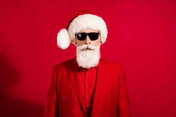 Wall Mural - Portrait of attractive bearded grey-haired man wearing festal cap winter event festival costume isolated over bright red color background