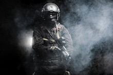 Professional Special Forces Fighter In A Helmet And With Special Weapons Shrouded In Smoke On A Black Background.