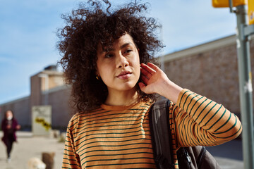 Wall Mural - Cute young woman touching her hair outdoors