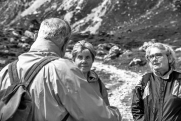 Poster - Elderly people relaxing at the end of a mountain hike, talking along the alpin trail.