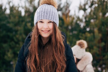 Portrait of a beautiful girl with long hair in a snowy forest. Winter in the woods. Girl walks in the winter forest