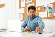 © Drobot Dean - Young brunette man working with laptop while sitting at desk in office