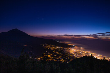 Aerial view of the night city lights and the mountain.