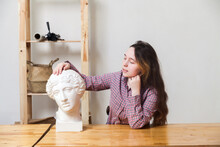 Teenage Girl Poses With   Plaster Head Of   Young Man
