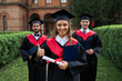 © Тарас Нагирняк - Graduate female shows like with her friends in graduation gowns holding diploma and smiling at camera