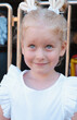 Prtrait of little happy funny girl with blond hair playing around in amusement park.
