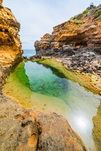 A Still Green Rock Pool At The Base Of A Rocky Sandstone Canyon At The Coast
