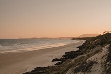 A Deserted Beach And Headland During Sunset.