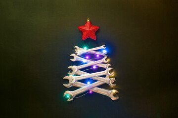 creative christmas tree on black background, made of wrenches. industrial greeting card and happy ne