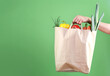 Hand holding paper bag with vegetables empty space green background.Online market,internet supermarket and orders.