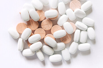 White and colored pills on a white background. Oblong and round pills close-up. Healthcare and medicine.	