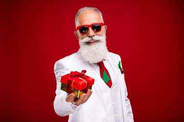 Sticker - Photo of funky elder grey hair santa man give present wear eyewear white jacket isolated on red color background