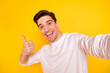 © deagreez - Photo of funky brunet young guy do selfie show thumb up wear shirt isolated on yellow background