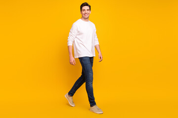 Canvas Print - Full body profile photo of cute brunet millennial guy go wear shirt jeans sneakers isolated on yellow color background