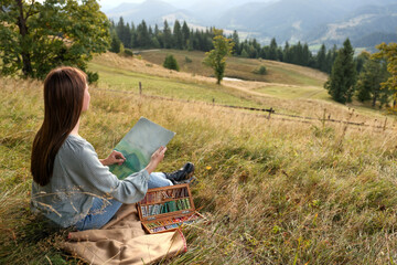 Sticker - Young woman drawing landscape with soft pastels in nature. Space for text