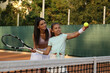 © New Africa - Mother teaching daughter to play tennis on court