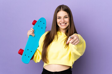 Wall Mural - Young caucasian woman isolated on purple background with a skate and pointing to the front