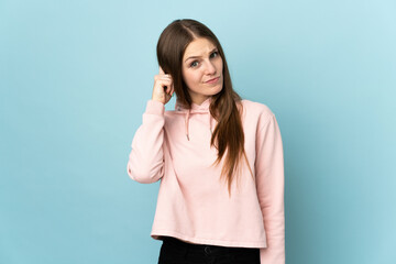 Wall Mural - Young caucasian woman isolated on blue background having doubts