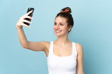 Wall Mural - Young caucasian woman isolated on blue background making a selfie