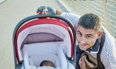 Canvas Print - Man looking at his newborn child inside the cradle. Love and happiness concept