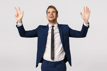 Hallelujah I got promoted. Pleased and relieved, thankful successful young blond male entrepreneur in classic suit, raising hands sky, look up thanking god pleased, express gratitude white background