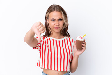 Wall Mural - Young Russian girl holding cappuccino isolated on white background showing thumb down with negative expression