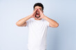 © luismolinero - Young Moroccan man isolated on blue background shouting and announcing something