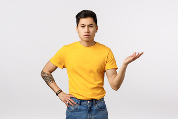 So what. Skeptical and pissed, frustrated young asian guy dont understand whats big deal, why so fuss, raising arm in dismay, standing puzzled and bothered as arguing with friend, white background