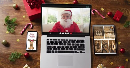 Poster - Happy senior caucasian santa on video call on laptop, with smartphone, tablet christmas decorations