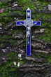 Niebieski krzyż z medalikiem św. Benedykta na naturalnym tle.
