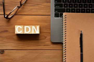 Poster - On the table there is a word cube lined CDN with laptop computers and glasses. It is an abbreviation for the word Content Delivery Network.