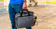 Close up, young casual man hand holding laptop bag .