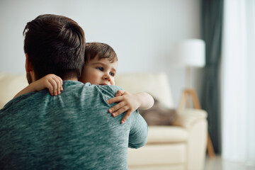 Wall Mural - Affectionate little boy and his father embrace at home.