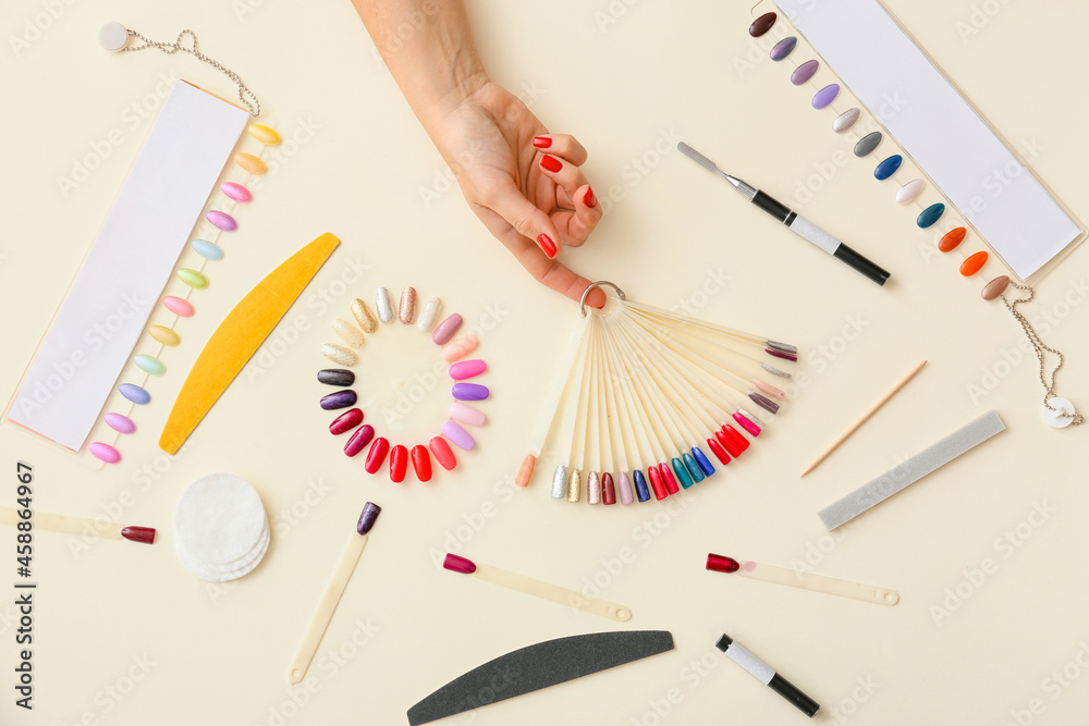 Female hand with nail polish tips and tools for manicure on color background
